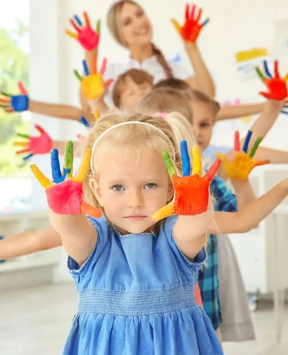 Children with a leader with painted hands during an art class