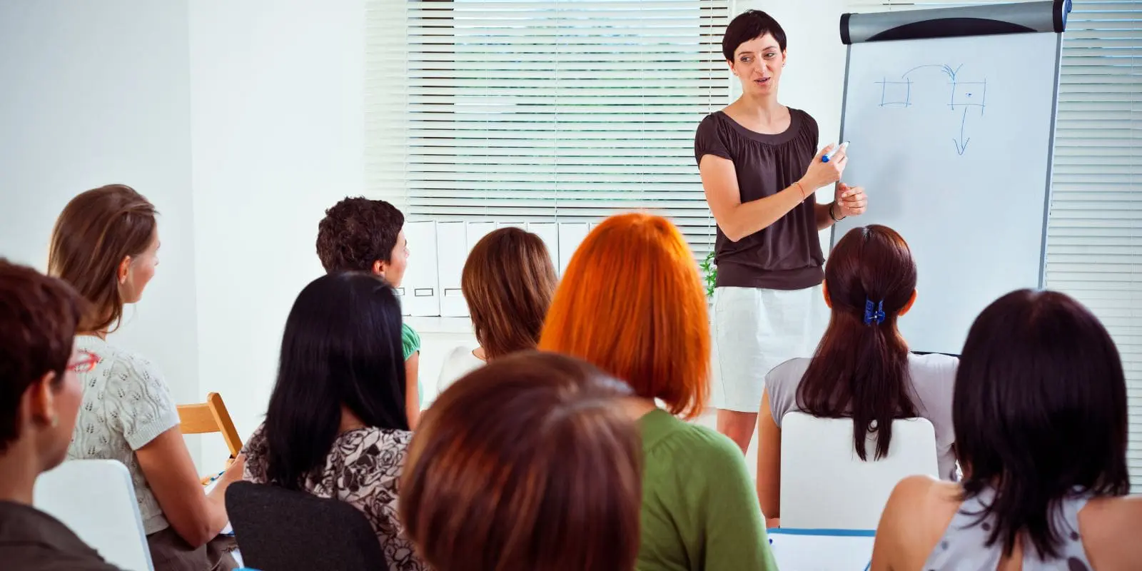 A lady trainer in front of a group of people in an organisation.