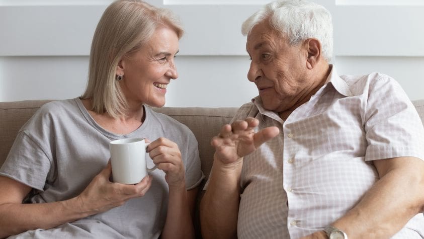 Older man and younger woman chatting on a sofa.