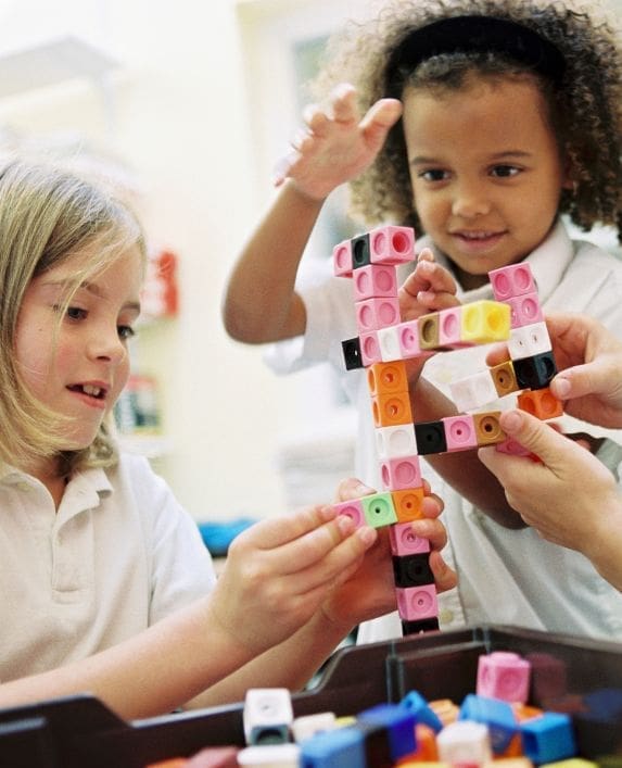 Two girls playing in an after school club playing with building blocks