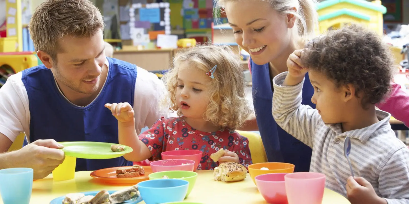 Children eating in a early years setting with their early years practitioners.