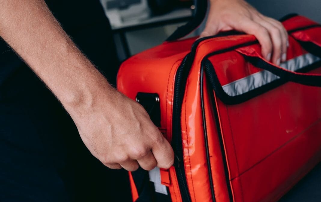 Man zipping up an red emergency grab bag.