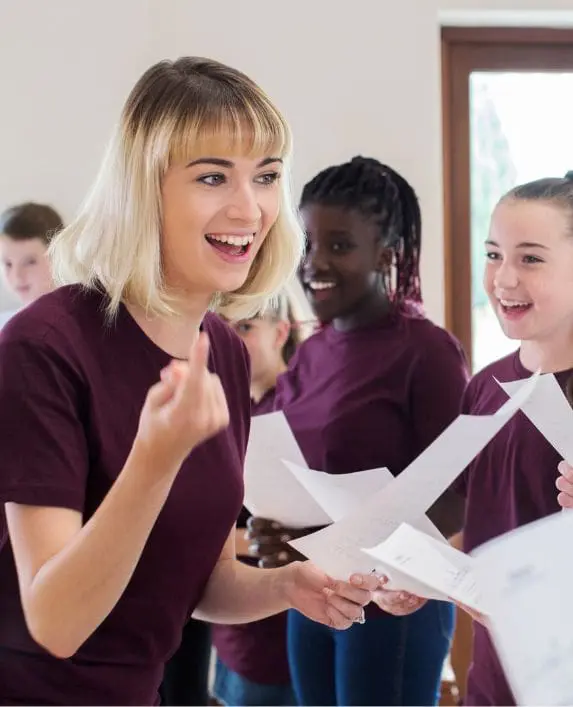 Lady running a choir with a group of children