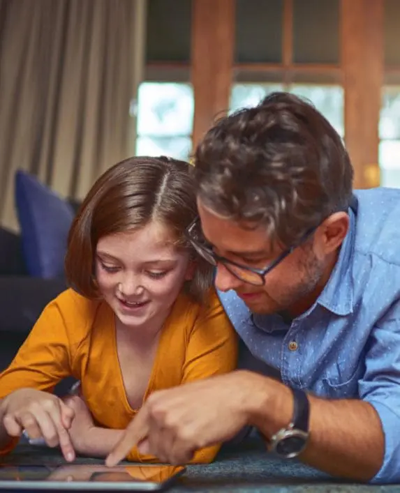 Father and daughter looking at at tablet in their home.