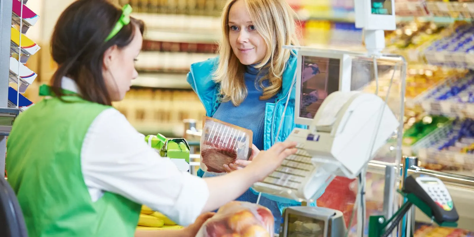 Checkout lady in a supermarket serving a woman customer.