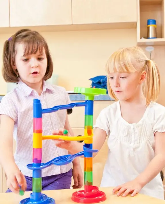 Two children playing with a marble run at nursery.