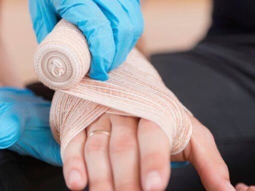 First aider bandaging a person's hand due to an injury at work.