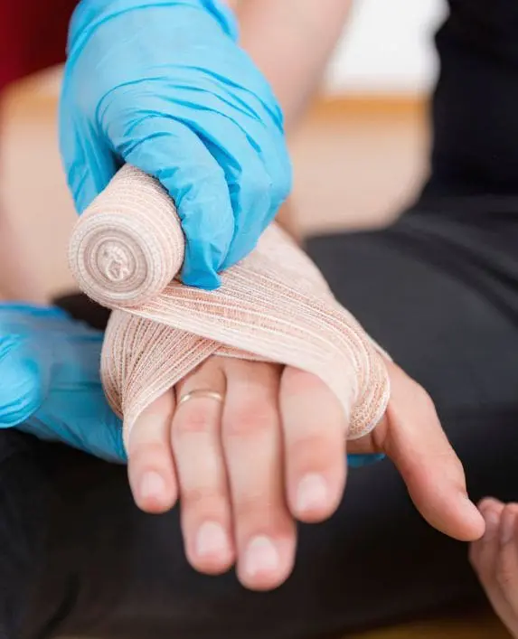 First aider bandaging a person's hand due to an injury at work.