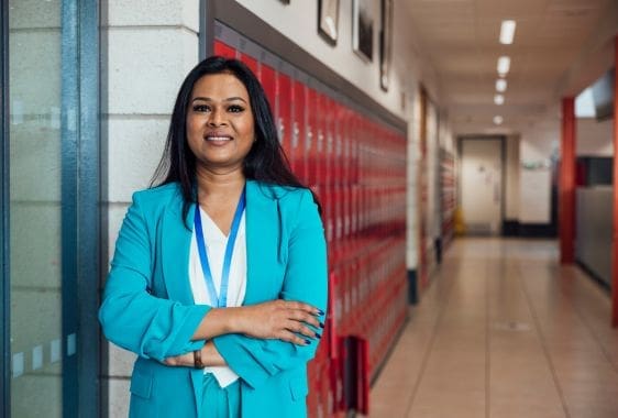 Head teacher with a school behind her Head teacher with a school behind her.