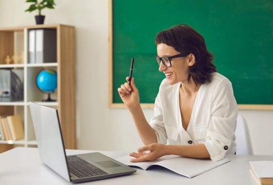 Teacher working at a laptop Lady wearing headphones looking at her laptop