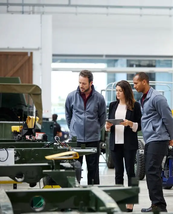 Three people in a business setting observing some sort of production line.