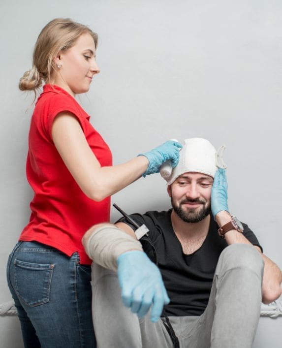 A lady doing a head bandage in a first aid course
