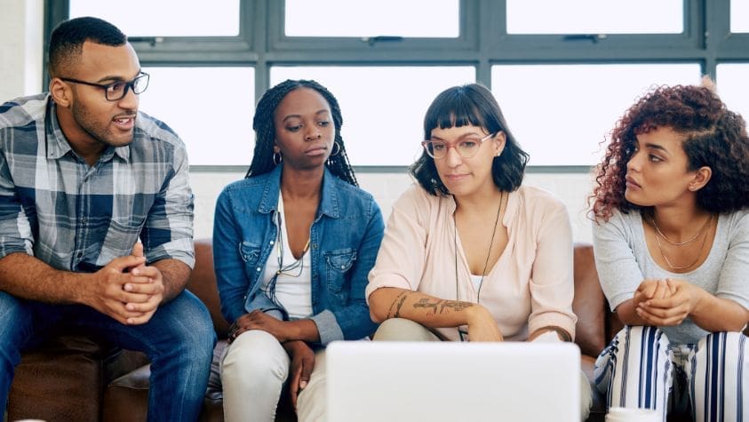 A group of adults discussing something around a computer.