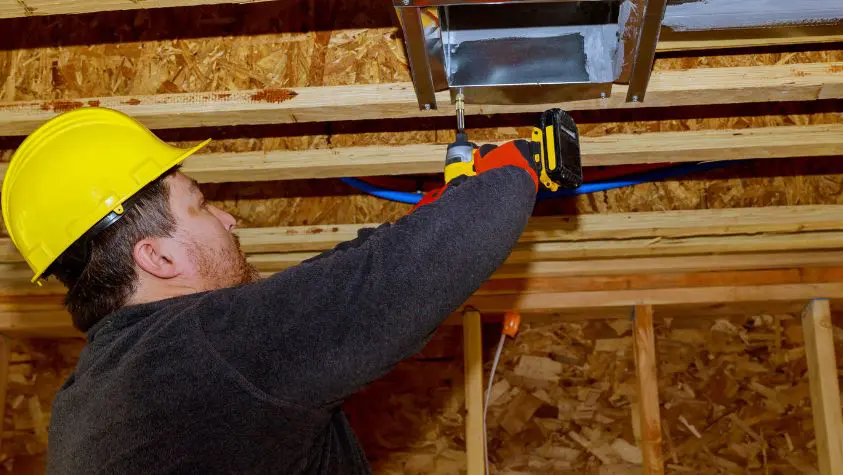 A man maintaining the air conditioning system in a building.