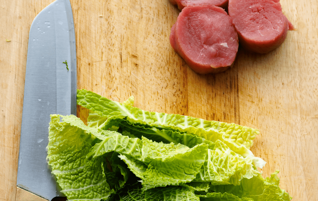 A picture of meat and lettuce on the same chopping board.