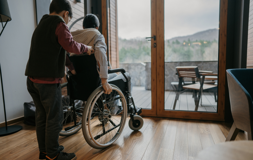 Image of a young carer pushing somebody in a wheelchair.